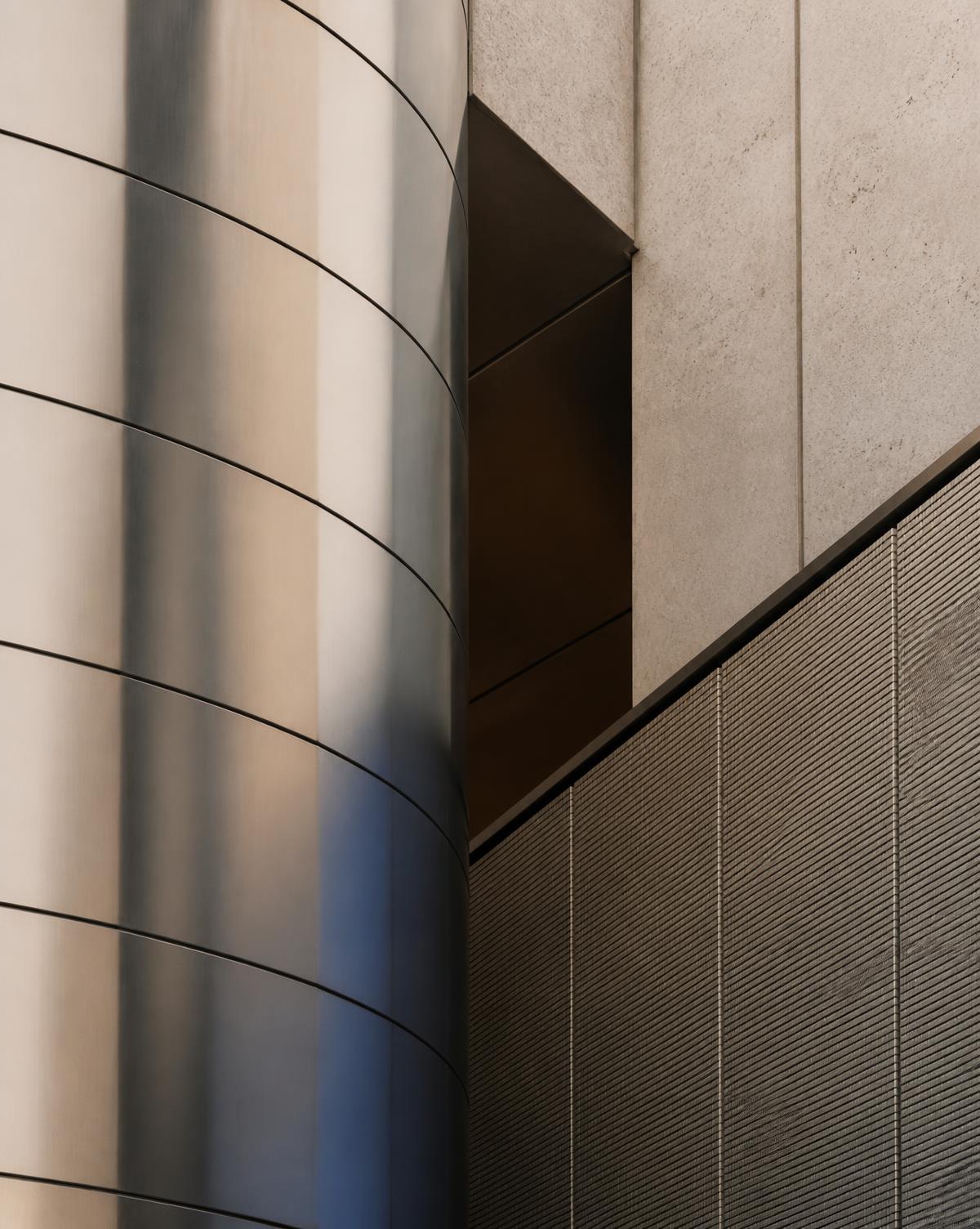Abstract detail of a curved metal facade beside textured concrete panels